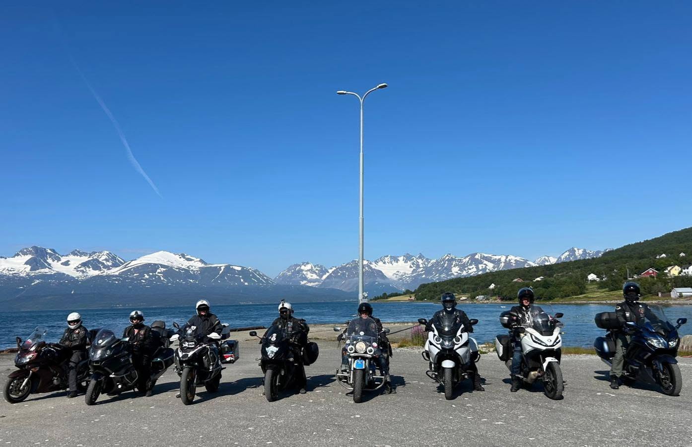 Grupa motocyklistów Right Riders na tle wody i ośnieżonych gór podczas wyprawy na Nordkapp w 2025 roku