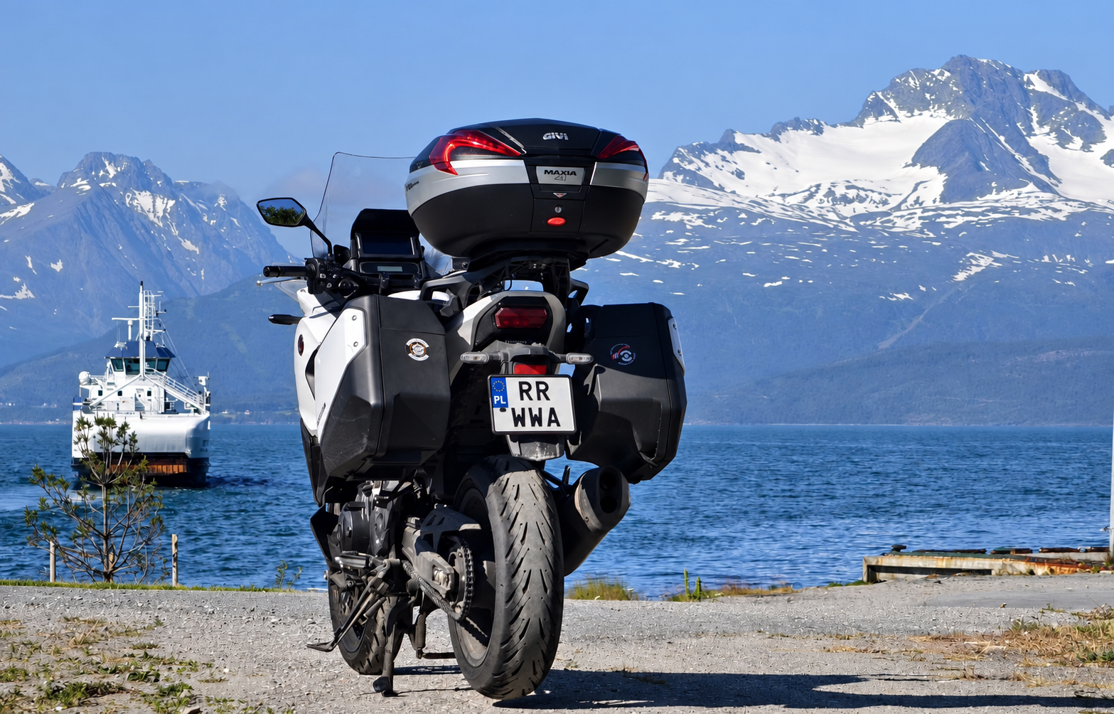 Motocykl Right Riders nad wodą, z promem i ośnieżonymi górami w tle — Nordkapp 2025